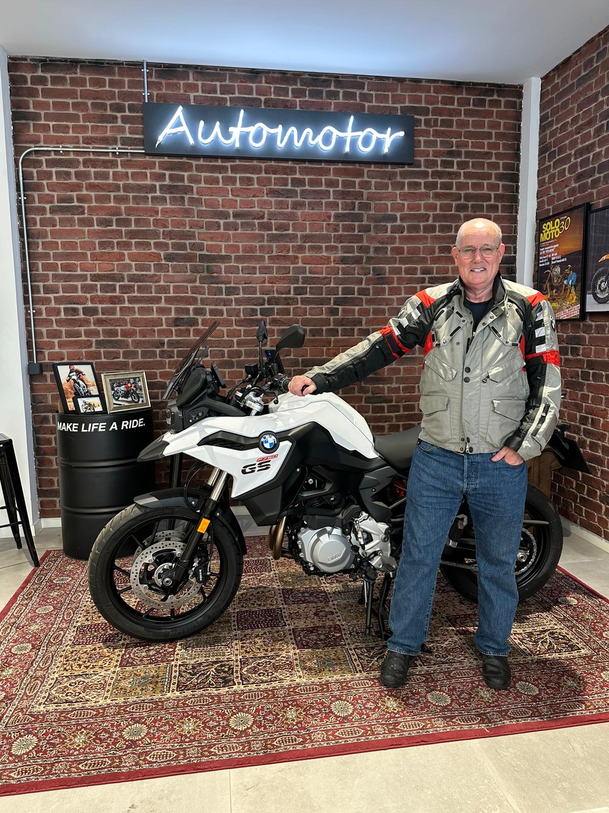 Standing next to my new white BMW F 750 GS motorcycle in the dealership on collection day